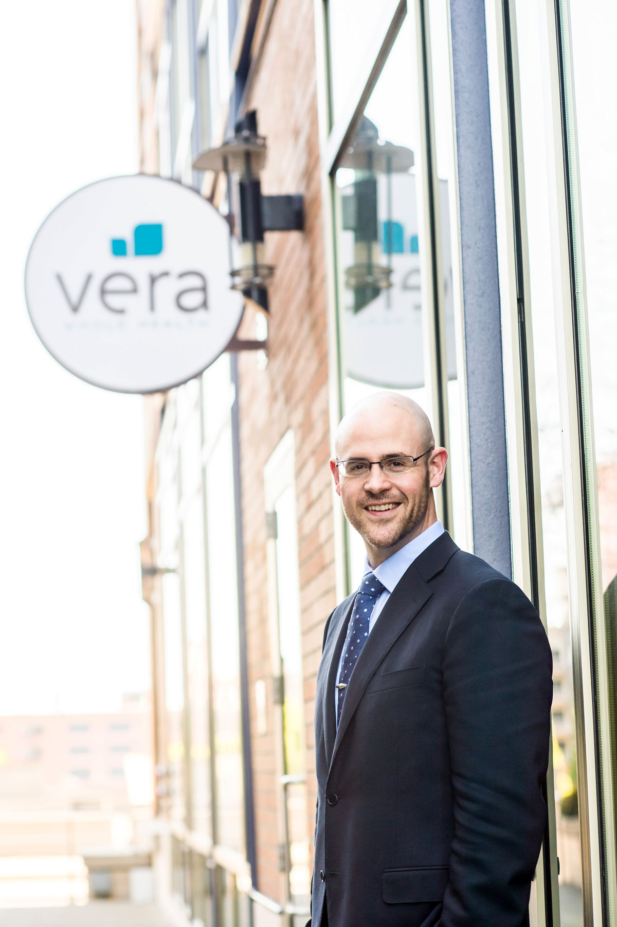 Ryan Schmid, ’07 MBA, smiles in a suit and tie, in front of Vera Whole Health building signage.