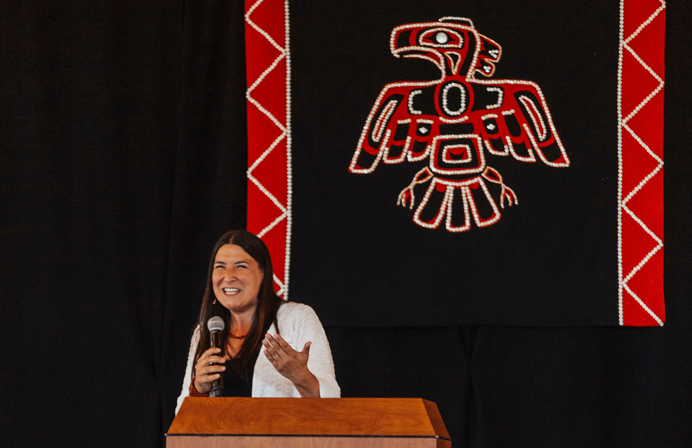 IPI Director Christina Roberts on stage at a dinner hosting the tribes of Western Washington and honoring the work of Father Pat with the tribes.