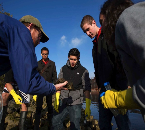 Faculty shows students items at the Duwamish River.